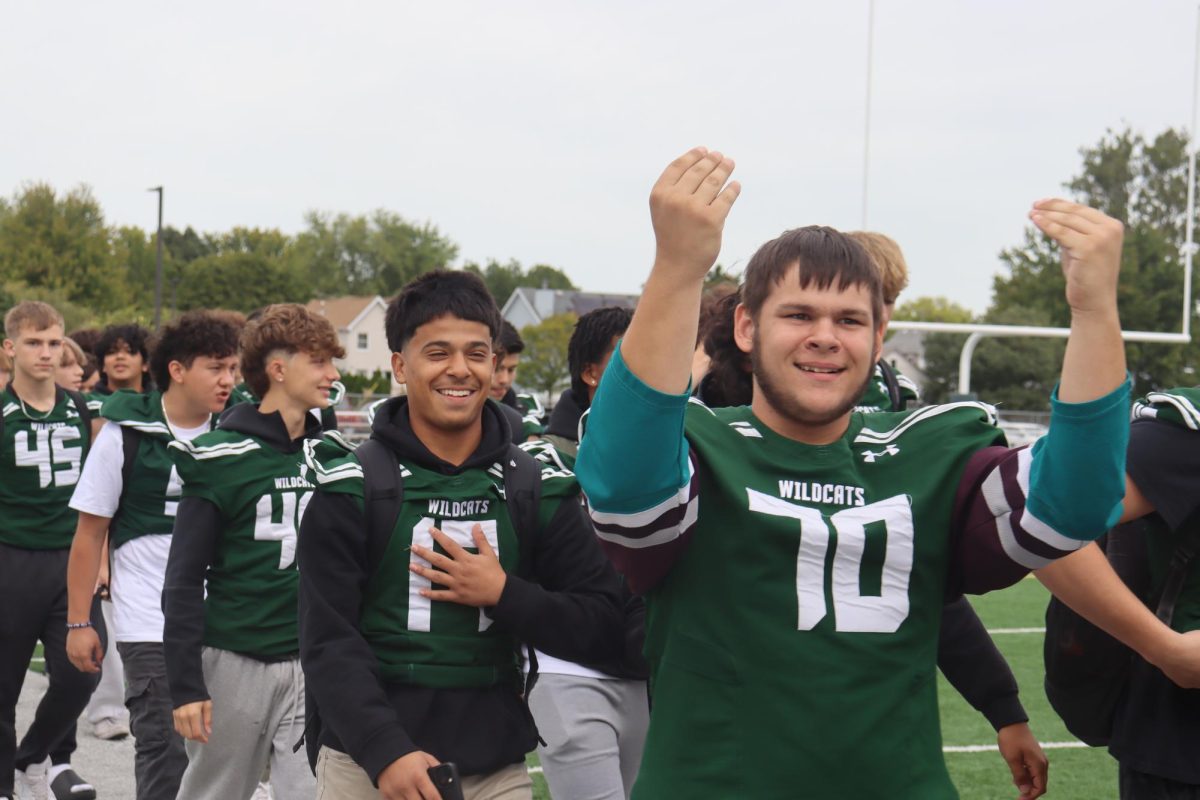 Football team members smiling as they walk across the field.