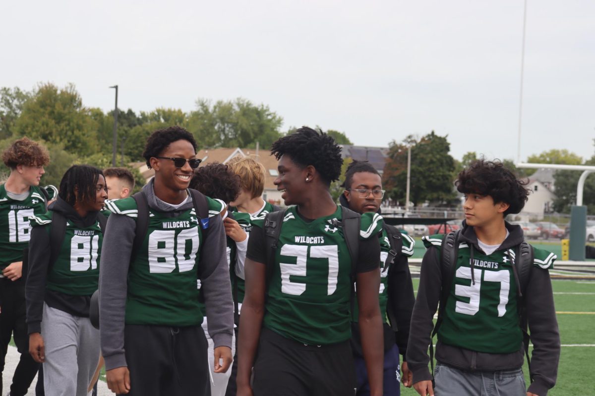 Football team members smiling as they walk across the field at the Pep Rally.