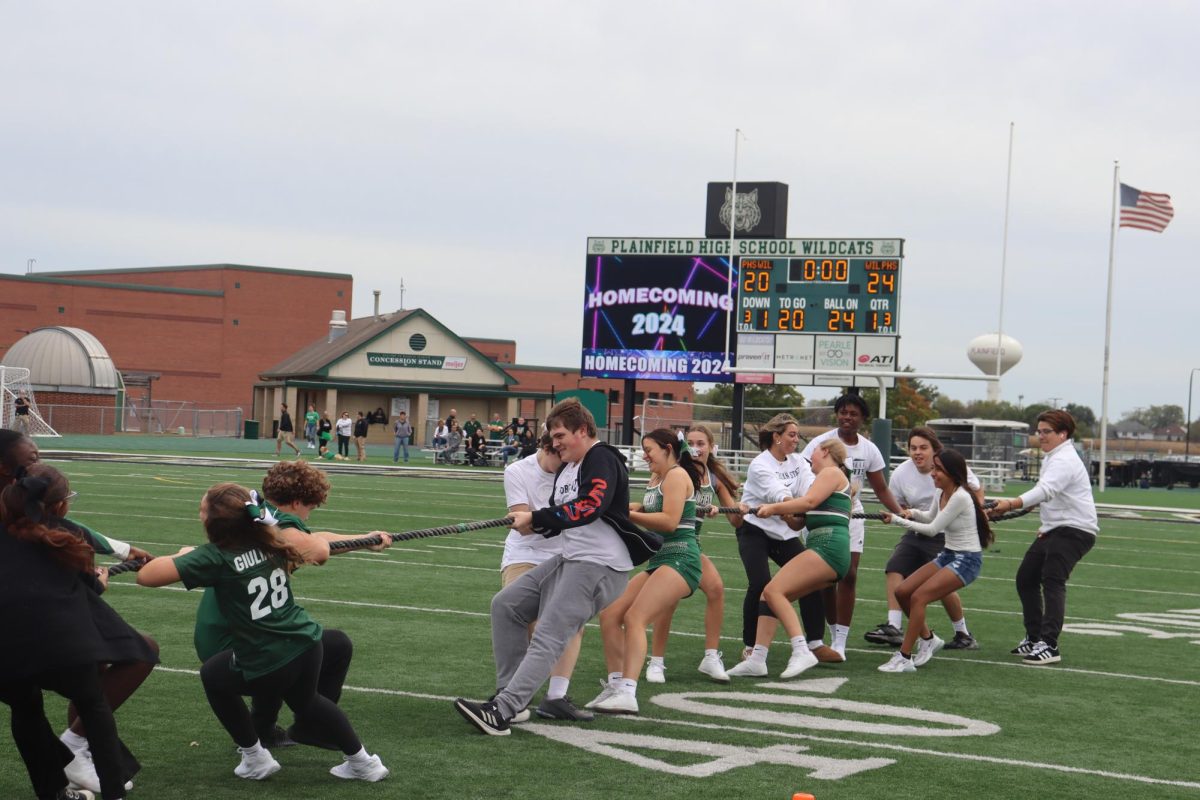 The Juniors dragging the freshman team across the field in victory during the first round of Tug a War.