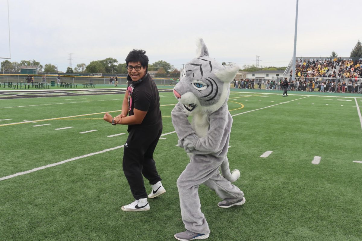 Senior Juan Garcia-Rivera and Willy the Wildcat flexing on the field during the Pep rally.