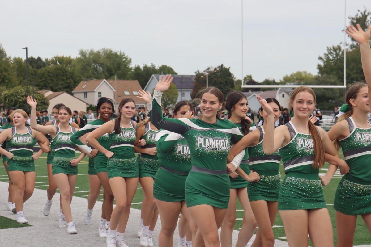 Cheer team waving to the students while entering the pep rally.