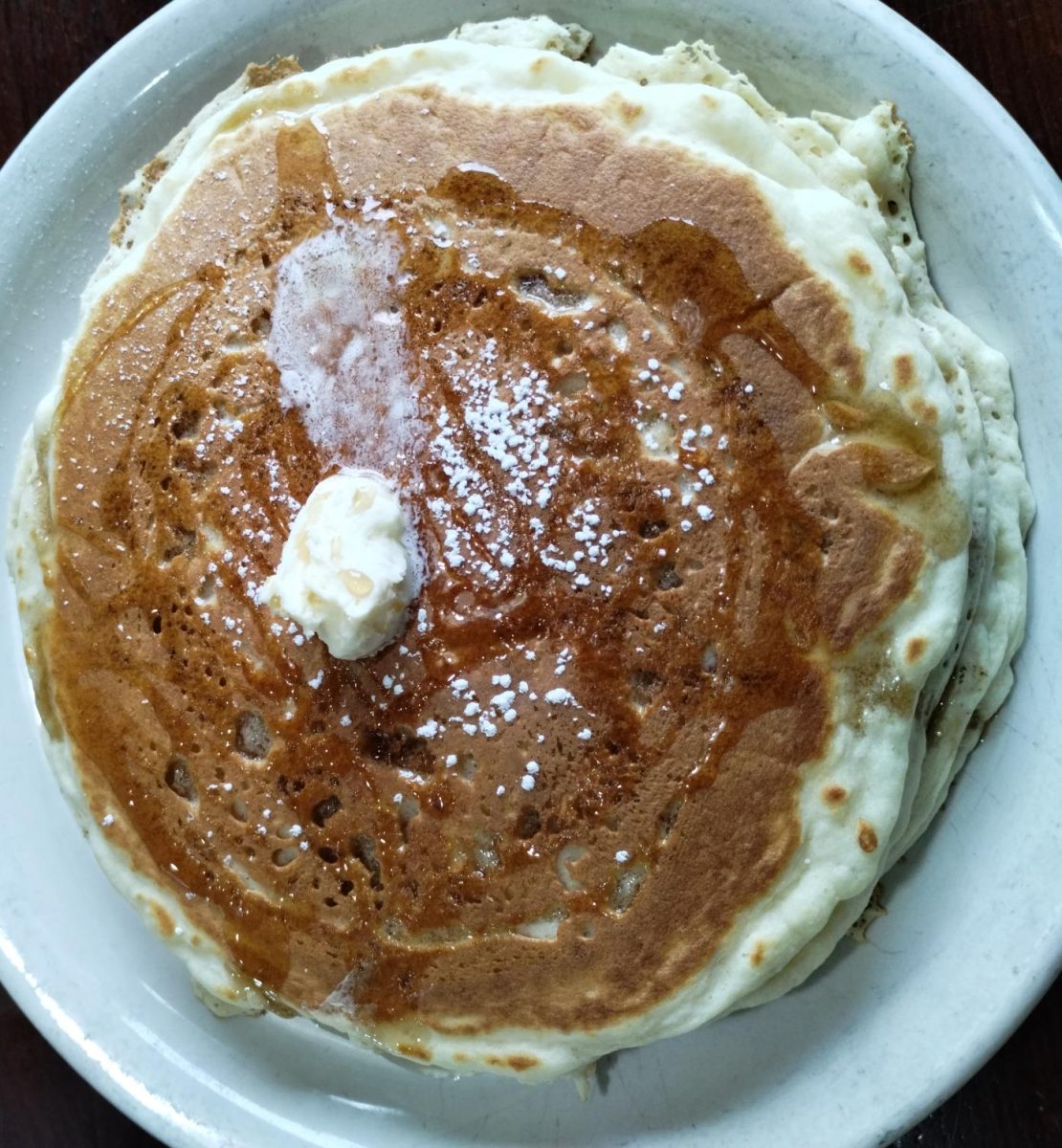 Three fluffy pancakes covered with butter and syrup came as a side order to the main dish.