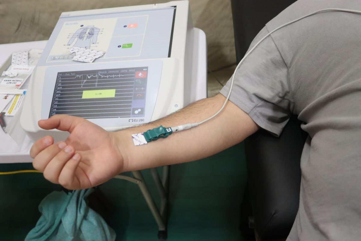 A student waits for the EKG machine to finish detecting their heart rate patterns.